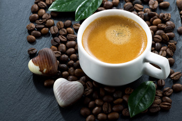 cup of espresso on coffee beans background and chocolate candies