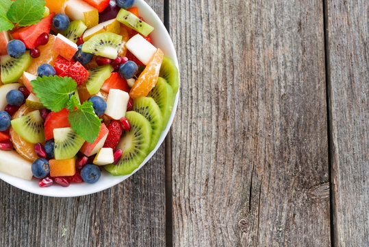 Fruit and berry salad and wooden background, horizontal