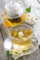 kettle and a cup of green tea with jasmine on wooden table