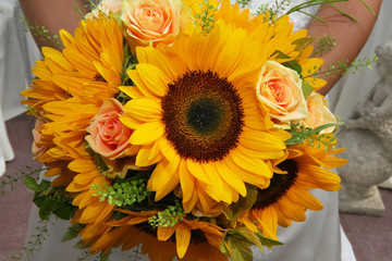 Bride holding a beautiful bouquet made of sunflowers and roses