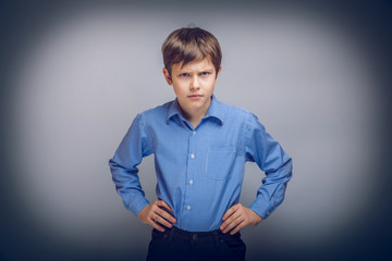 teenager boy angry hands on hips gray background cross proc