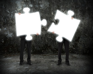 Glowing puzzles businessmen hold to connect illuminating dark co