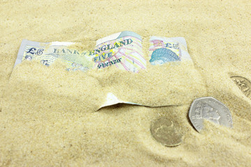 British Currency buried by sand.