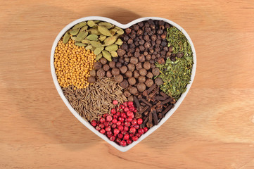 Different dry spices in plate in form of heart