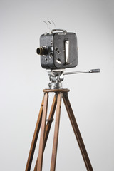 a movie camera on a tripod isolated on white
