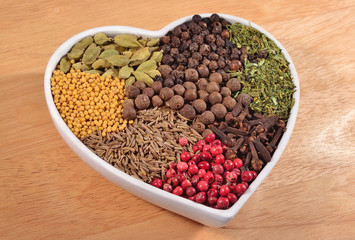 Different dry spices in plate in form of heart