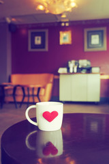 vintage color tone of  cup of coffee with red heart on the table
