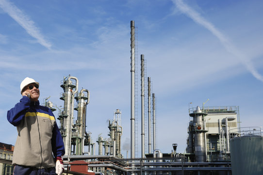 oil worker in front of large refinery industry