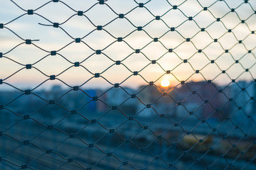 Blurred cityscape beyond metal fence
