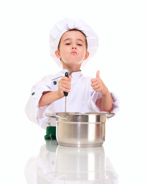 Little satisfied boy chef with ladle stirring in the pot