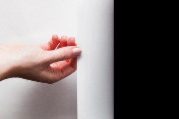 Hand pulling edge of paper to uncover, reveal something