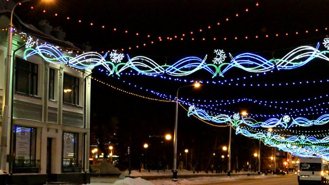 Festively decorated night street with the passing cars