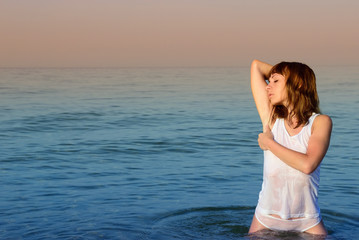 Fototapeta na wymiar Girl in a white T-shirt and shorts in the sea