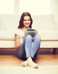 smiling teenage girl with tablet pc at home