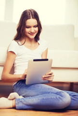 smiling teenage girl with tablet pc at home