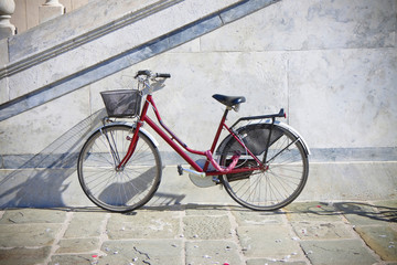Fototapeta na wymiar Red bicycle with basket against a marble wall