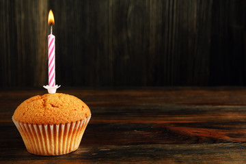 Cupcake with candle on wood