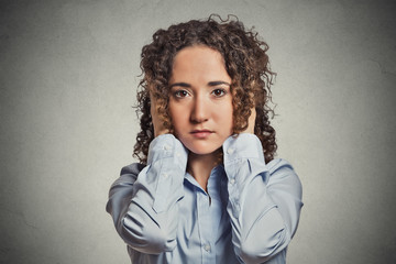 young woman covering her ears with hands grey wall background 