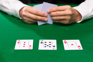 poker player holding playing cards at casino table