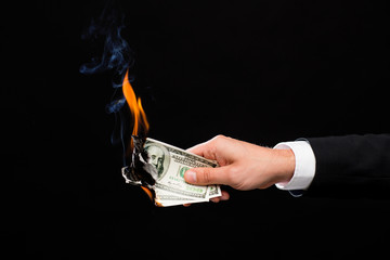 close up of male hand holding burning dollar money
