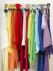 Close up on color coordinated clothes on hangers in a store.