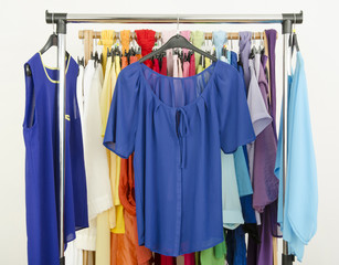 Wardrobe with colorful cute blue outfits displayed on a rack. 