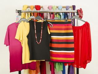 Wardrobe with colorful cute summer clothes displayed on a rack.