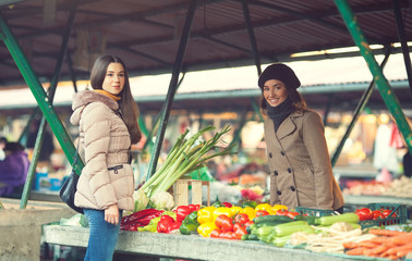 Obraz na płótnie Canvas Young woman buying vegetables at market