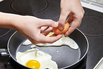 Keuken spatwand met foto Woman breaks an egg in fried eggs © Sergey Ryzhov