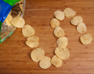 Potato chips coming out of a bag onto a wood board