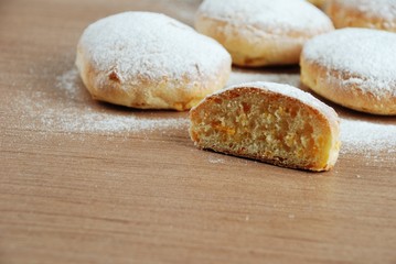 Bun with powdered sugar on a wooden table