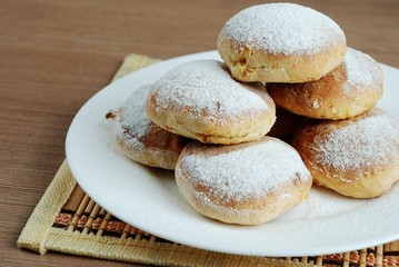 Bun with powdered sugar on a wooden table