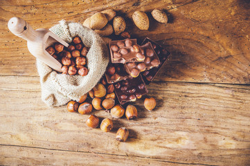 milk chocolate with hazelnuts and walnuts in a sack on a wooden