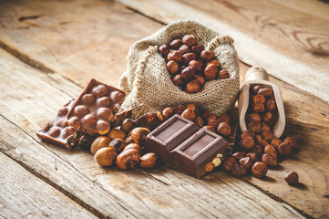 milk chocolate with hazelnuts and walnuts in a sack on a wooden
