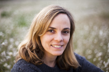 Chica rubia sentada entre margaritas