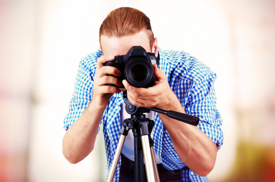 Handsome Photographer With Camera On Tripod Indoors