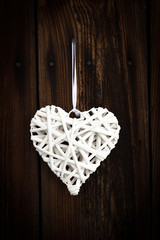 White wicker heart on wooden background