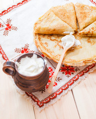 Pancakes with a sour cream on wooden table