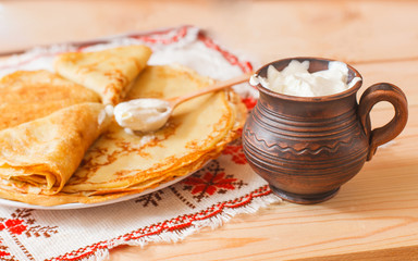 Pancakes with a sour cream on wooden table