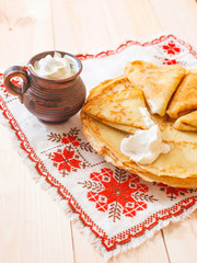 Pancakes with a sour cream on wooden table