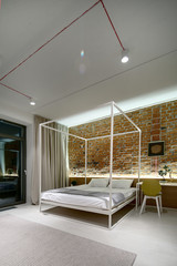 Bedroom in a modern loft style. Brick wall without plaster. Bed