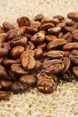 Roasted coffee beans on burlap background.