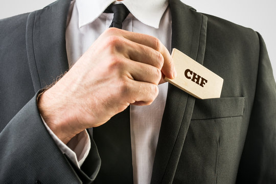 Businessman removing a wooden card with CHF sign
