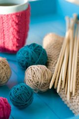 Bright balls of yarn, wooden knitting needles, knitted blanket