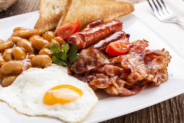 Full english breakfast with bacon, sausage, fried egg, baked bea