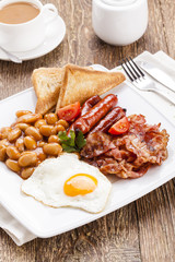 Full english breakfast with bacon, sausage, fried egg, baked bea