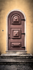 Old wooden door with metal hinges and lock on the yellow wall. T