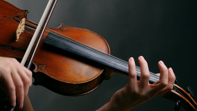 Woman playing violin over dark background. 4K, UHD