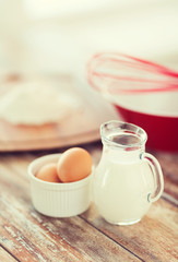 Obraz na płótnie Canvas jugful of milk, eggs in a bowl and flour