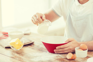 close up of male hand pouring milk in bowl